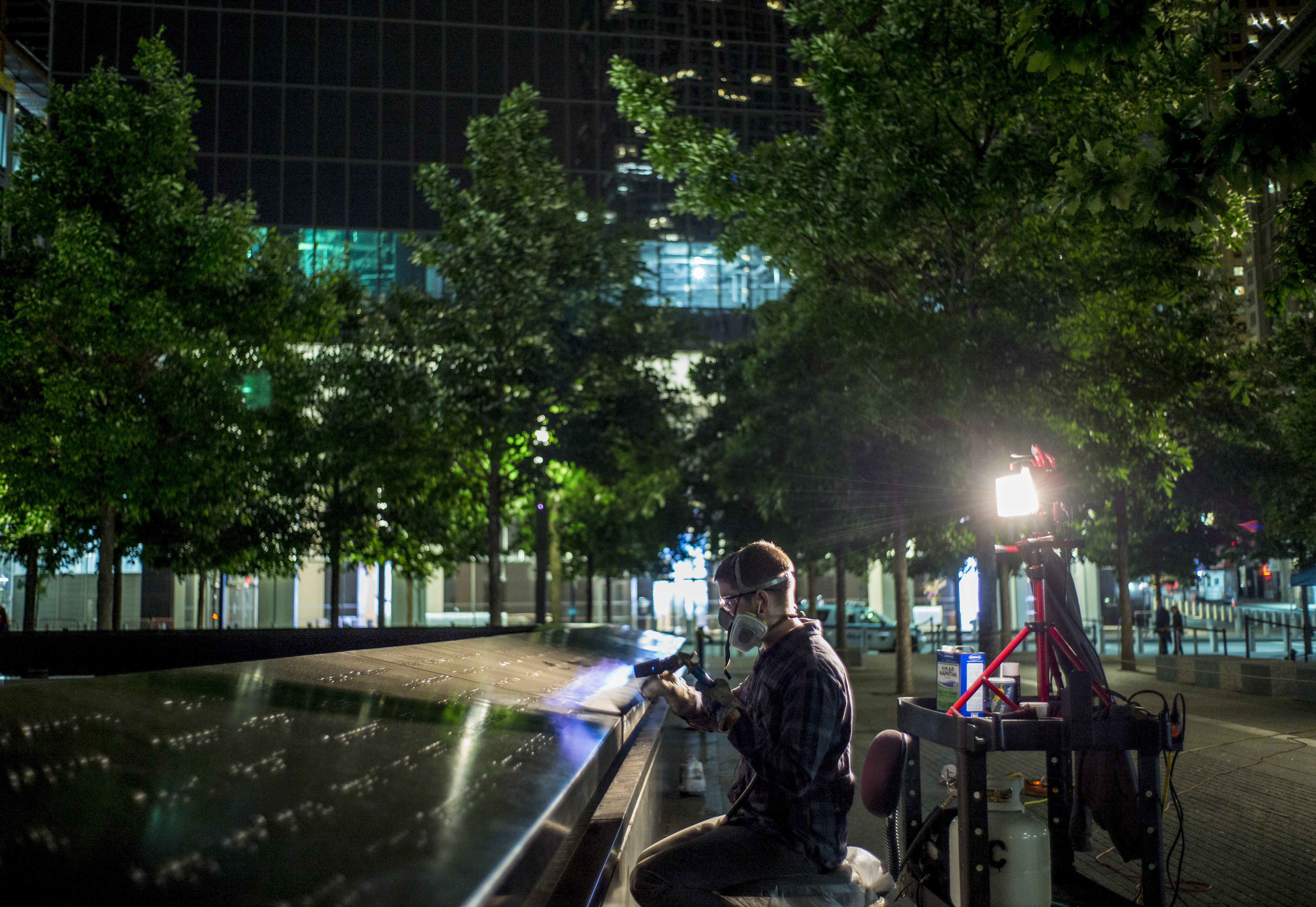 A person works on a bronze parapet at the south pool at night.