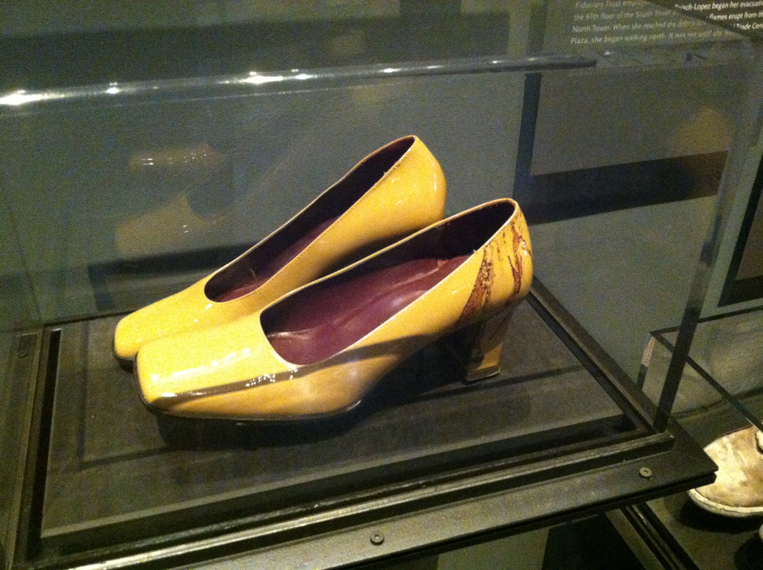 Two yellow high-heeled shoes belonging to Linda Raisch-Lopez are displayed in a glass case at the Museum. Dried blood is visible on the heel of the left shoe.