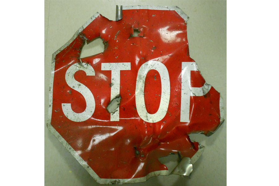 A heavily damaged red stop sign destroyed in the 1993 bombing of the World Trade Center is displayed on a white surface at the Museum.
