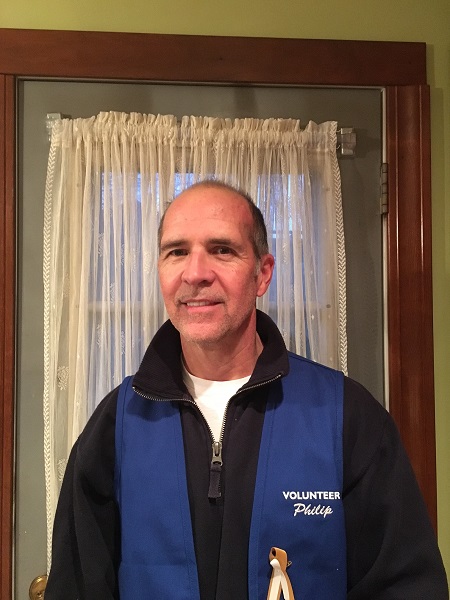 Port Authority employee Philip Caffrey poses for a photo in a blue volunteer vest. 