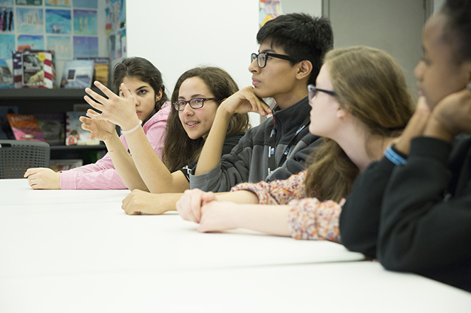 Five teenagers who are members of the second class of ambassadors sit at a table at the Museum.