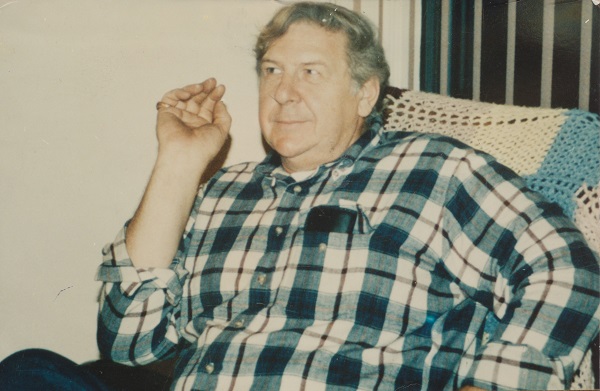 William Macko sits in a chair in a plaid shirt in this old photo.
