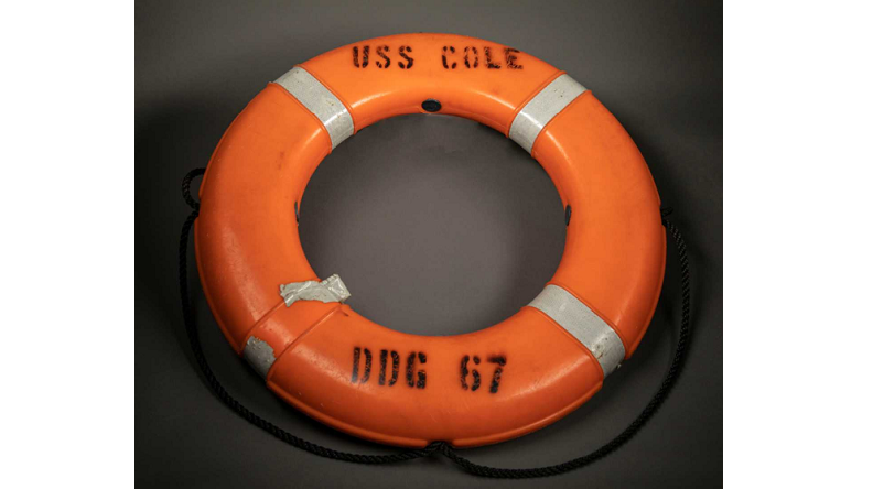 Orange life ring with the words "USS COLE" and "DDG 67" stamped on it.