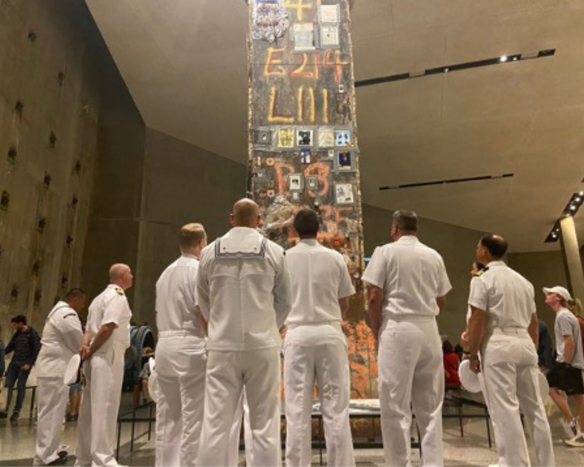 Back view of sailors in white uniforms looking up at Last Column in the Museum