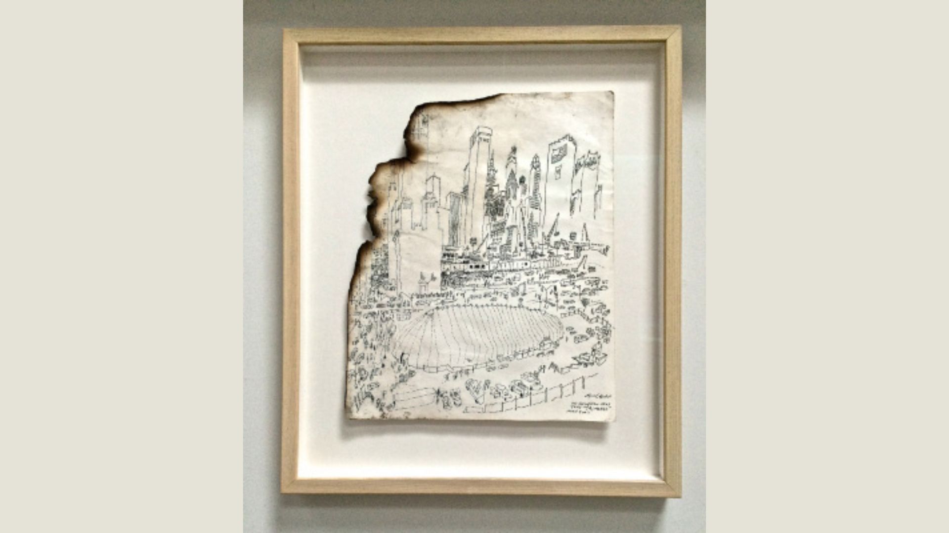 Framed drawing of altered lower Manhattan skyline, with upper left corner singed and missing a piece