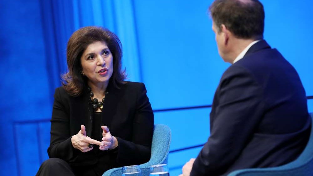 This close-up shot shows Author Farah Pandith gesturing with both hands as she speaks to Foreign Affairs editor Gideon Rose, who is in the foreground listening to her with his hands in his lap.