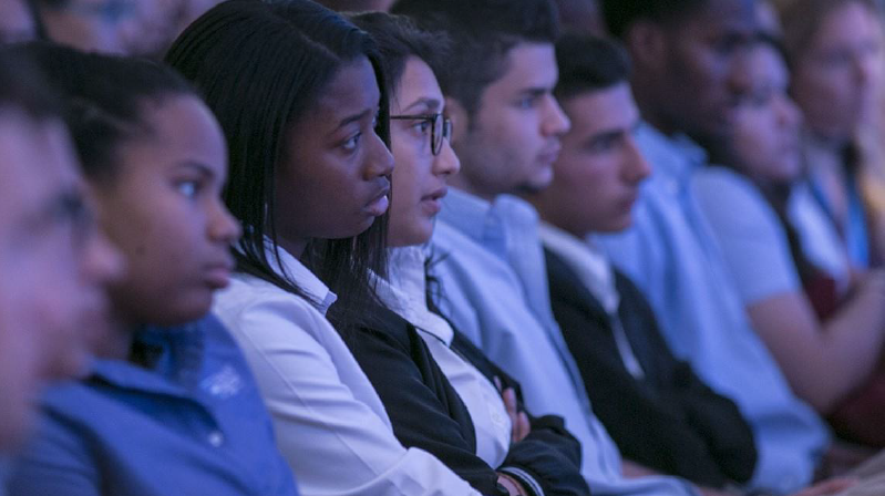 A row of seated teenagers who are focused intently on a presentation