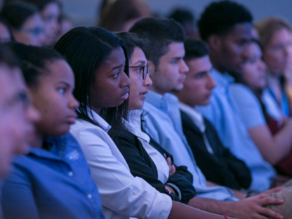 A row of students in an audience, listening intently