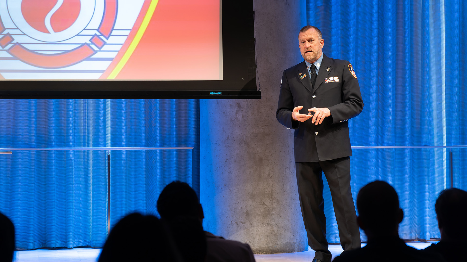 Tim Brown, in FDNY uniform, addresses a crowd from the stage