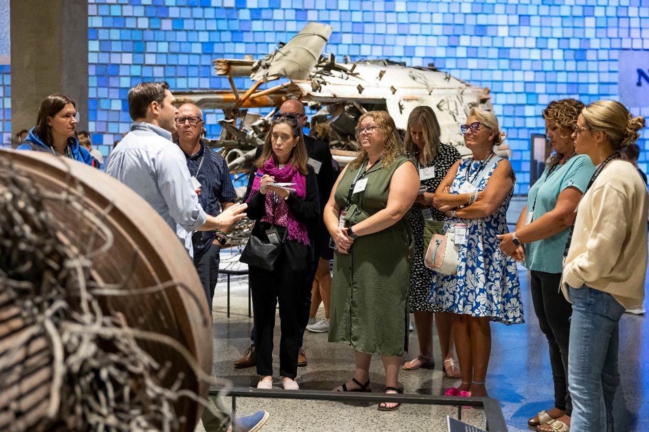 Teachers grouped together in front of the blue wall inside the museum