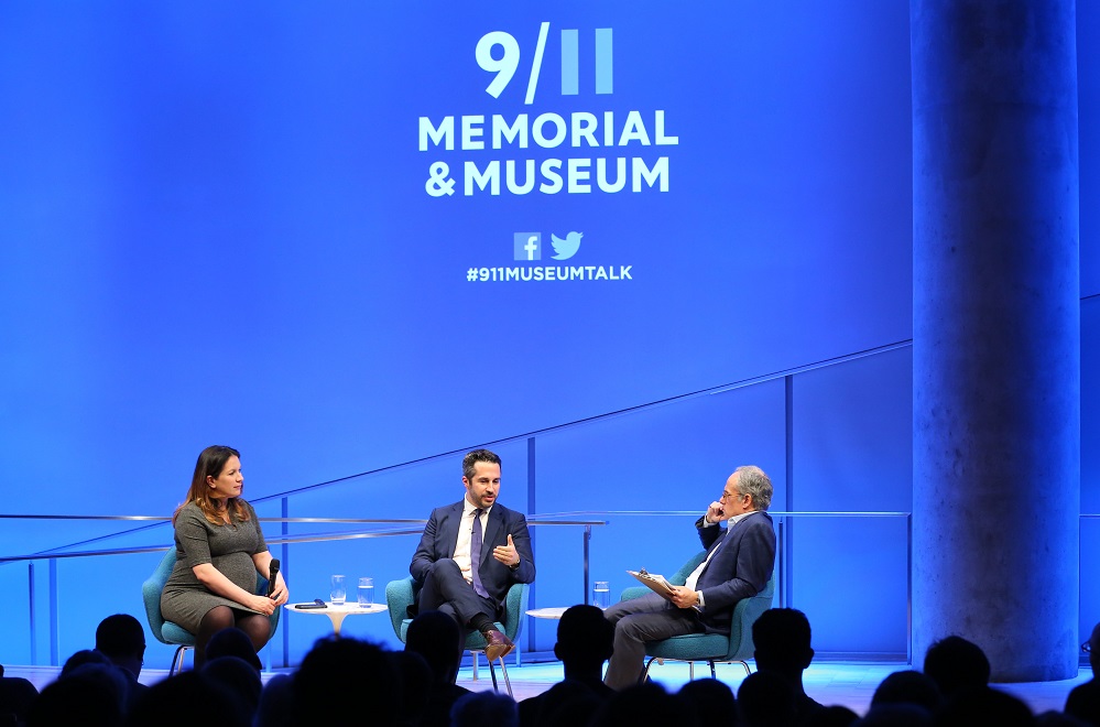 Lorenzo Vidino, director of the George Washington University Program on Extremism, speaks onstage at the Museum Auditorium while seated next to New York Times foreign correspondent Rukmini Callimachi and Clifford Chanin, the executive vice president and deputy director for museum programs. Vidino faces Chanin as he speaks and gestures with his left hand. Callimachi listens on to his right while holding her microphone in her lap. The wide-angle photo includes the audience, who are silhouetted by bright white