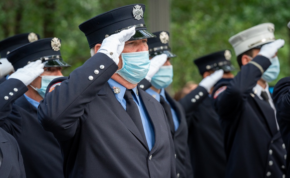 Members of first responder agencies, wearing face masks, salute.