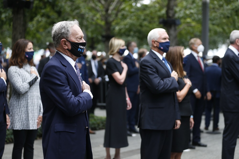 Elected officials stand on Memorial plaza and salute while wearing face masks and social distancing.