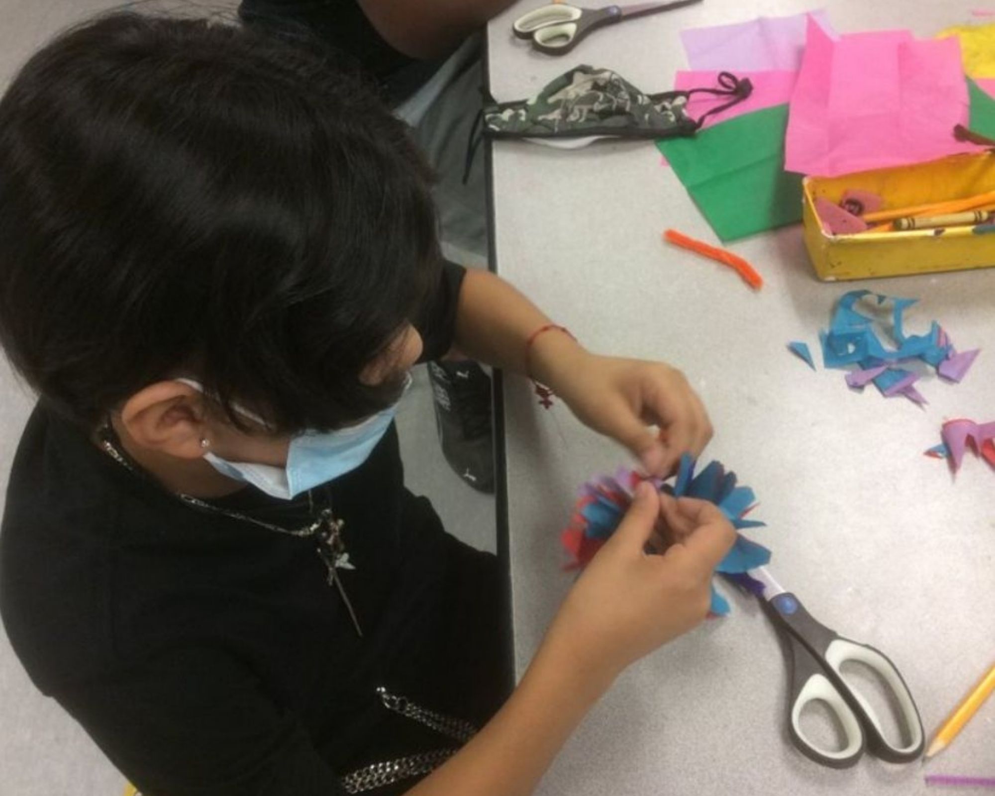 A young boy crafting flowers out of tissue paper