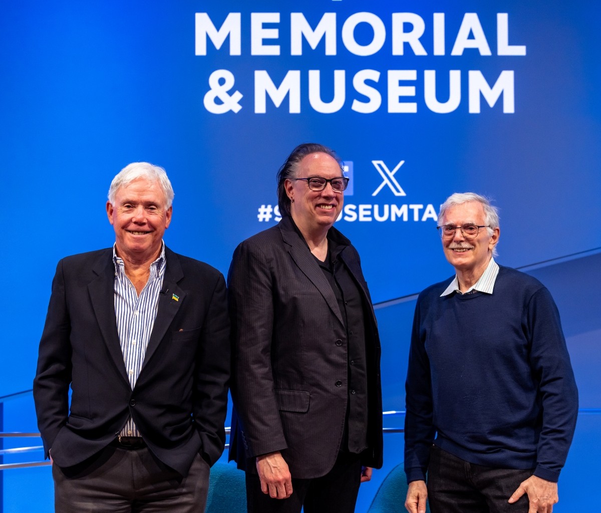 Three people stand smiling before the 911 Memorial & Museum logo