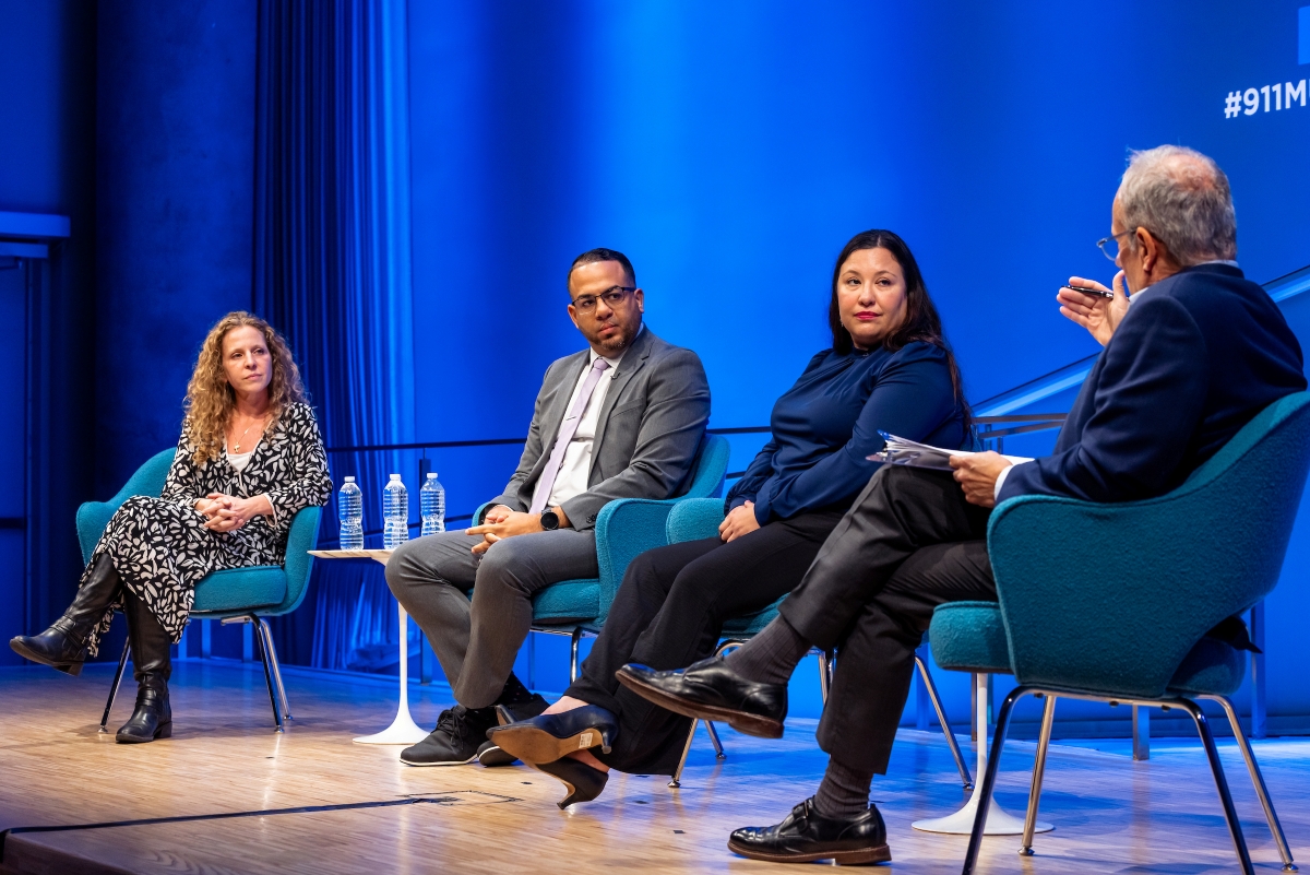 four people sit on stage under the 911 Memorial and Museum logo