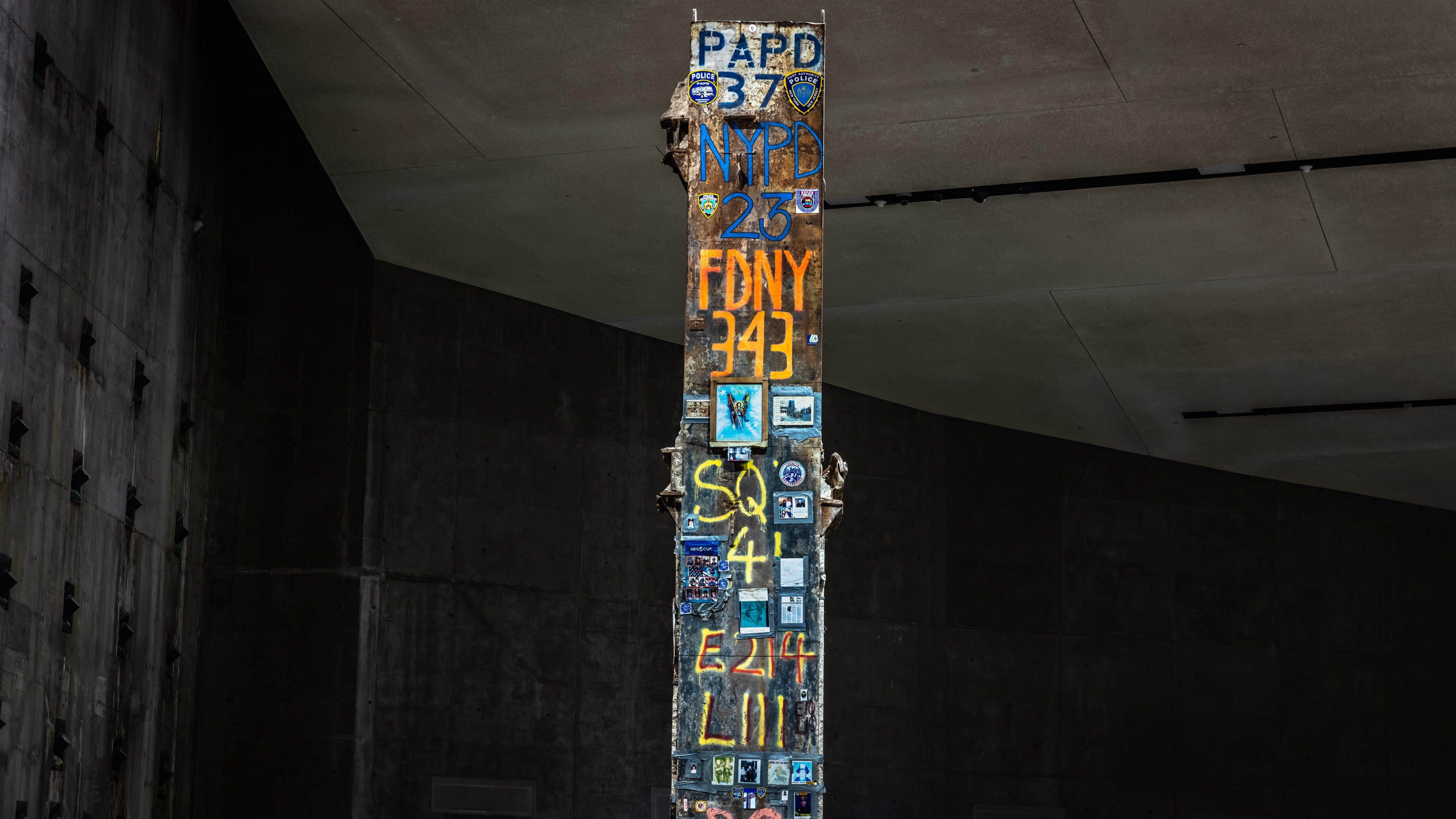The Last Column towers toward the concrete ceiling of the Museum. Pictures and written tributes to police and firefighters cover the sides of the column, listing the tally of the dead among first responders and rescue and recovery workers.