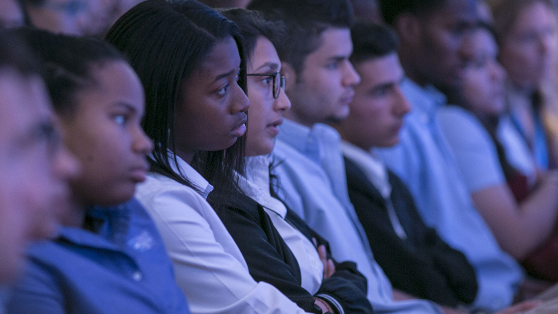 A group of students sit in the Museum auditorium for the Anniversary in the Schools webinar.