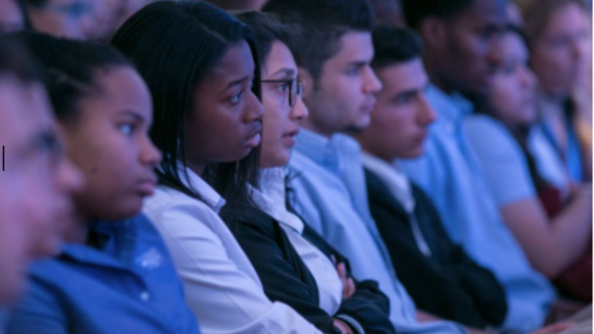 A row of students listen with attention.  