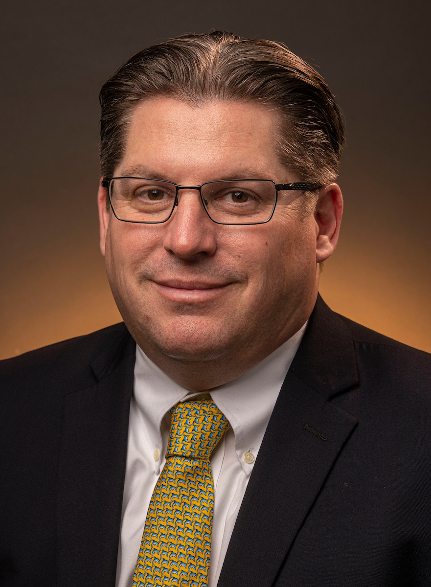 In this professional headshot, David Sheehan, the executive vice president and chief financial officer, looks directly at the camera and smiles. 