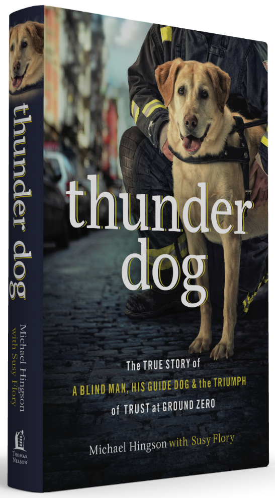A book cover of "Thunder Dog," featuring a yellow lab with a black collar standing on a city street. A firefighter kneels behind the dog, but his face is not visible.
