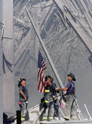 Three firefighters raise an American flag over rubble at Ground Zero