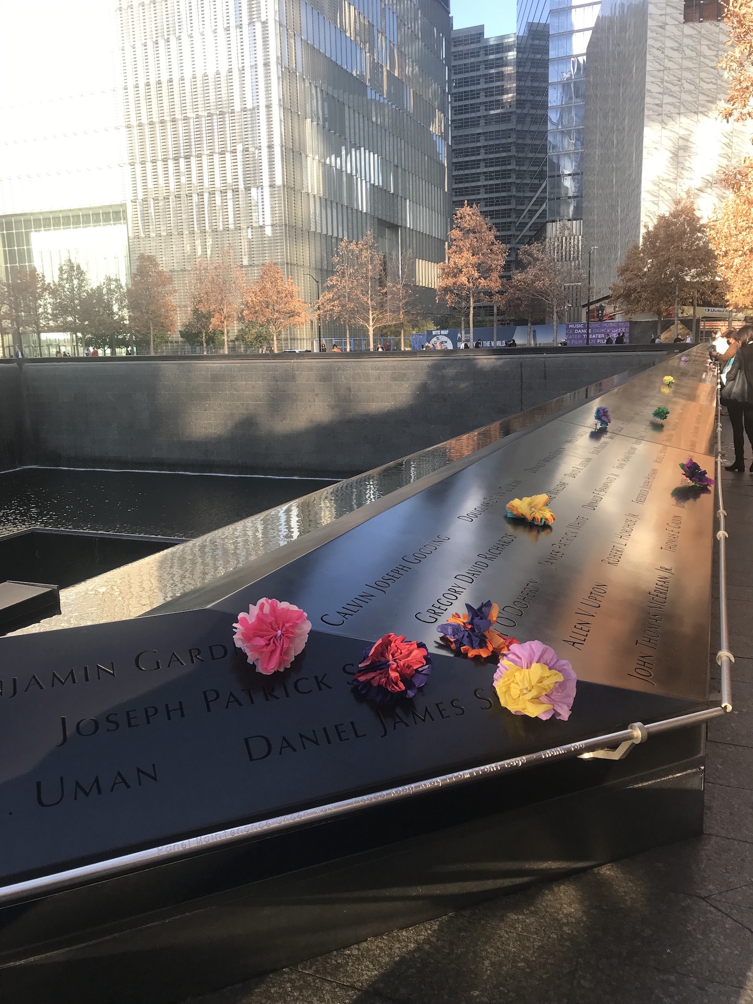 Handmade paper flowers placed at names along the Memorial 