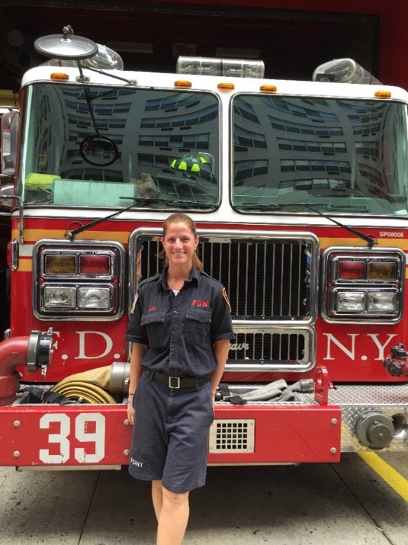 Josephine Smith stands, smiling and in uniform, in front of FDNY fire engine 39.