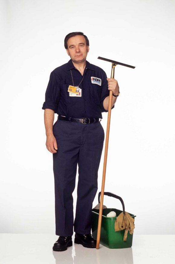 Jan Demczur in navy blue uniform holds a long-handled window squeegee and stands next to a bucket