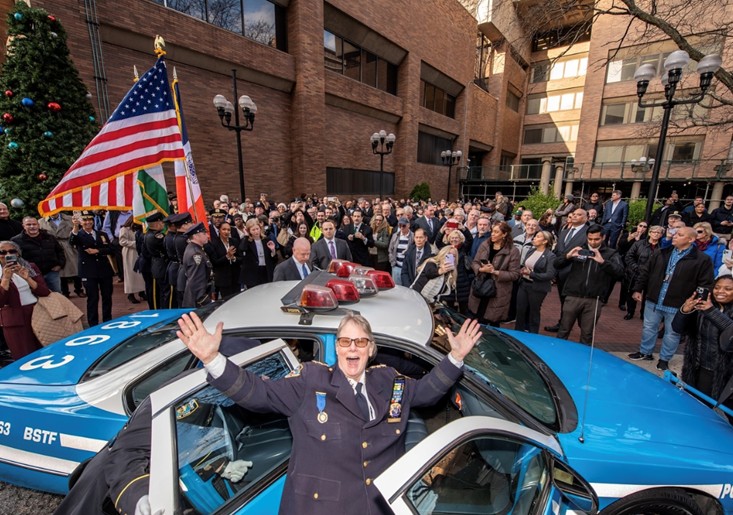 Chief Tobin stands by a police car, celebrating with other officers
