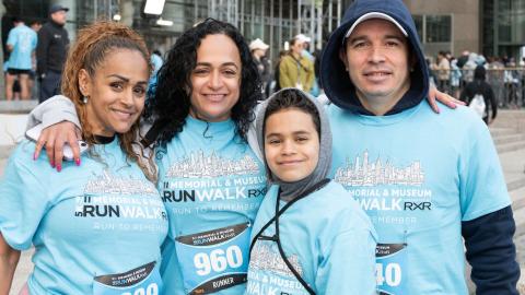 A group wearing 9/11 Memorial & Museum 5K t-shirts poses with their arms around each other