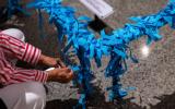 Hands tying blue ribbons at the base of the Last Column in the Museum