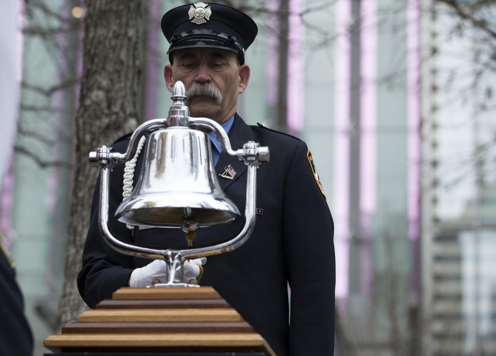 A mustachioed firefighter in a formal FDNY outfit rings a silver bell, marking the time the World Trade Center was bombed on February 26, 1993.
