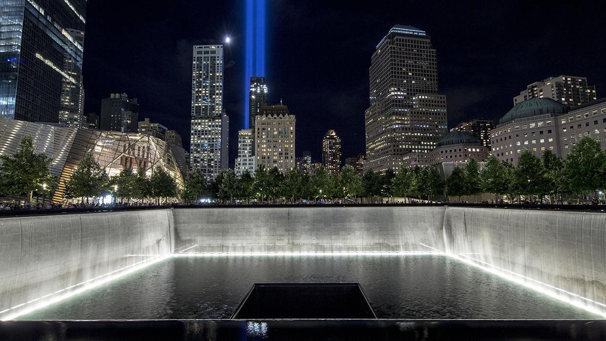 Night time on the Memorial plaza with the tribute in light illuminated in the background