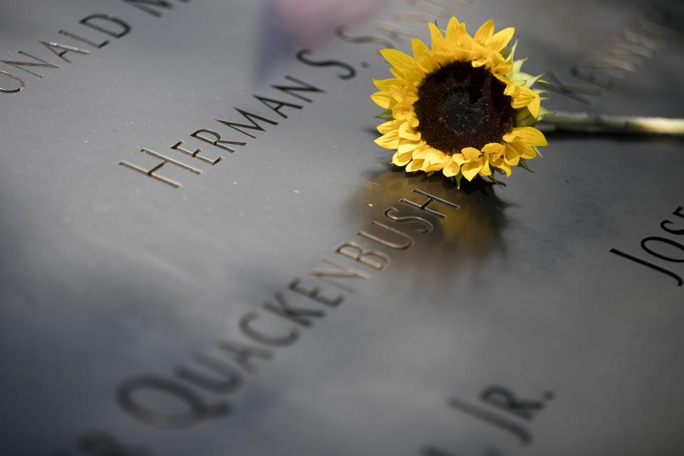 A yellow sunflower sits beside a name at the 9/11 Memorial.