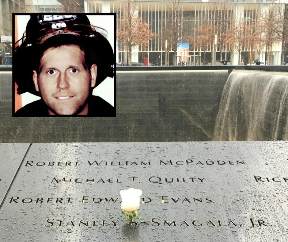 A white rose stands at the name of FDNY firefighter Stanley Smagala Jr. on a bronze parapet at the Memorial. An inset image is an old photo of Smagala in his FDNY bunker gear.