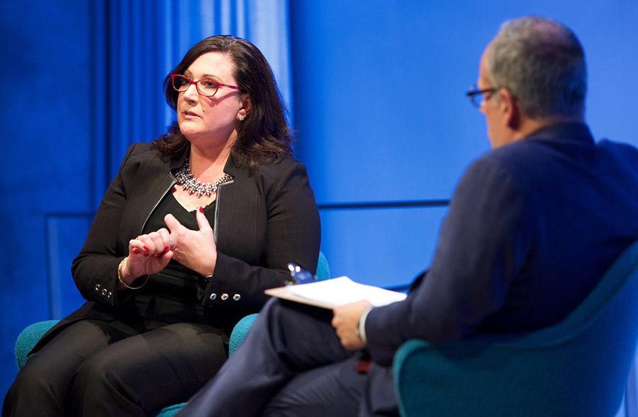 Retired FBI agent Mary Galligan speaks onstage at the Museum Auditorium during a public program. Clifford Chanin, the executive vice president and deputy director for museum programs, sits beside him with a clipboard on his lap.