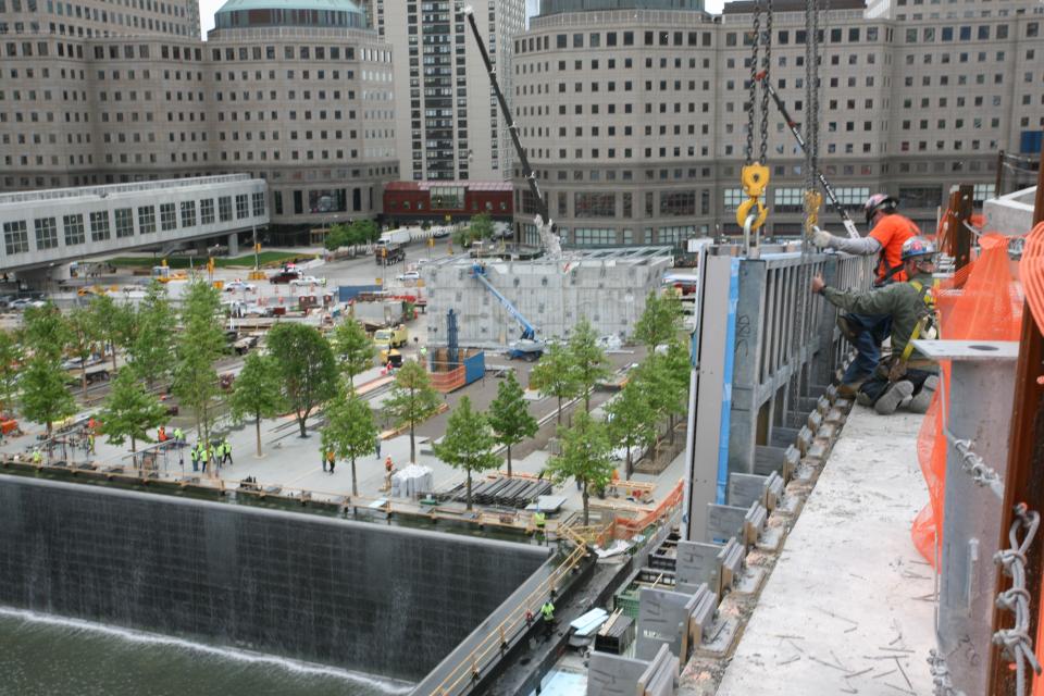 Construction workers atop the entry pavilion of the 9/11 Memorial Museum overlook the 9/11 Memorial. (Amy Dreher photo) WaterfallOverlookLens.jpg