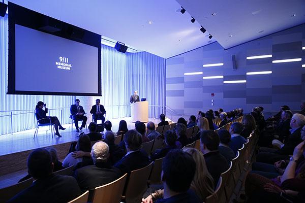 Dozens of audience members watch three men and a woman are seen onstage at the Museum’s Auditorium during a public program.
