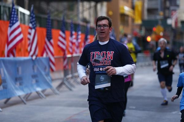 A man in an “Iron Workers” T-shirt runs the course at the 9/11 Memorial & Museum 5K Run/Walk and Community Day.