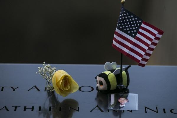 A stuffed bumble bee, a yellow rose, a small American flag, and a photo of a victim of the 9/11 attacks have been placed at a name on the Memorial.