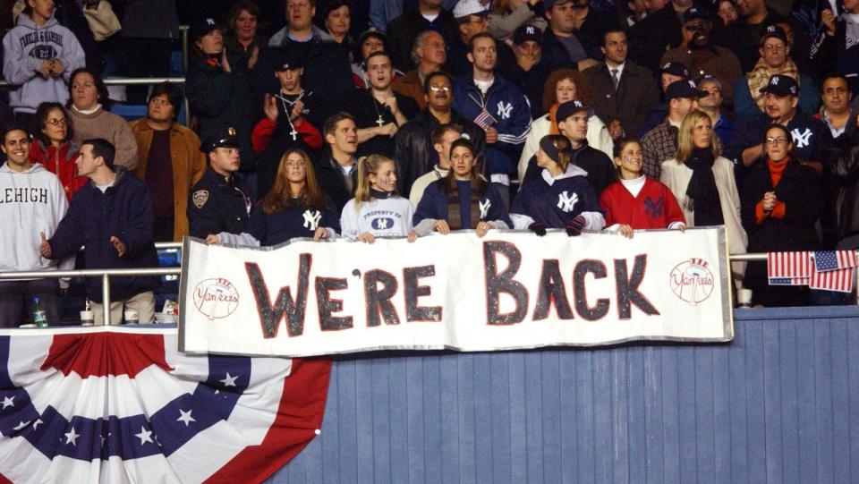 Yankees fans hold a sign reading “We’re Back” as they sit in the stands during a World Series game after 9/11.