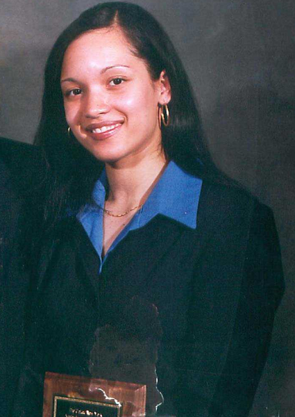 EMT Yamel Josefina Merino smiles while wearing a suit for a professional photo.