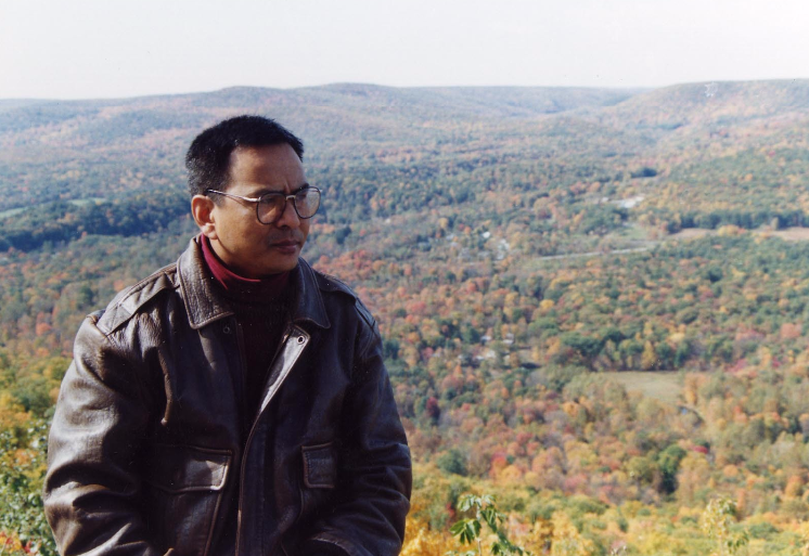 Jupiter Yambem poses for a photo in front of colorful, rolling hills on an autumn day.