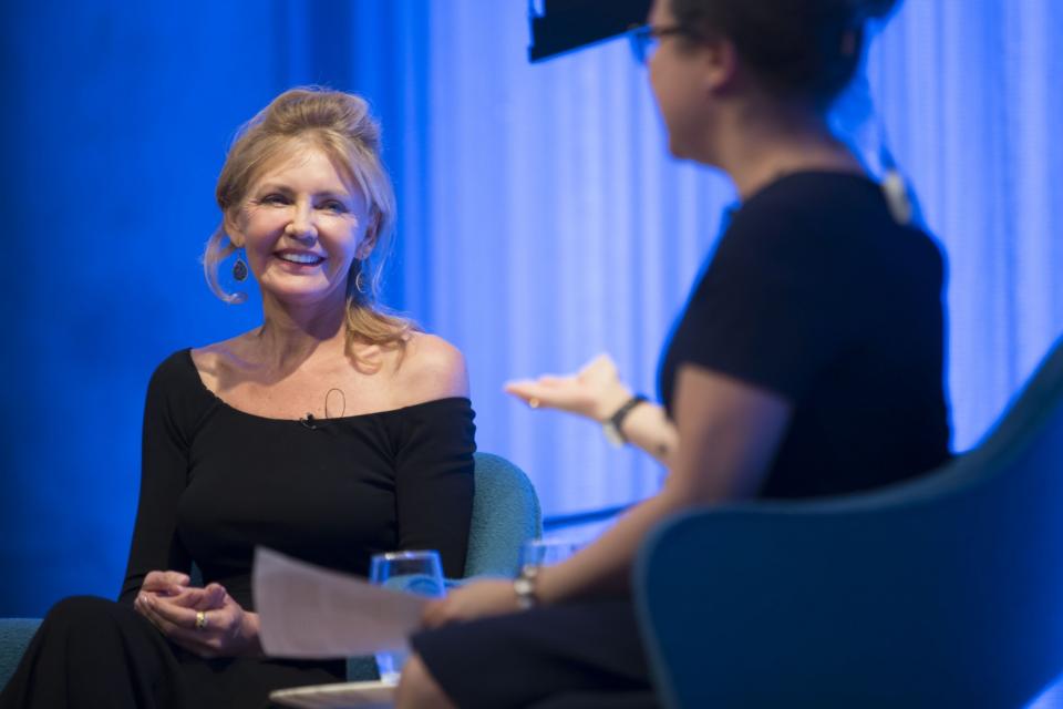 FEMA photographer Andrea Booher smiles onstage as she speaks with a woman out of focus in the foreground.
