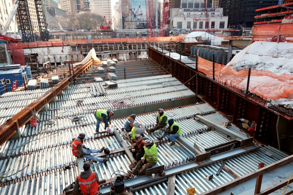 A group of construction workers work on the 9/11 Memorial in February 2011. Construction materials surround them as they work on a steel platform.