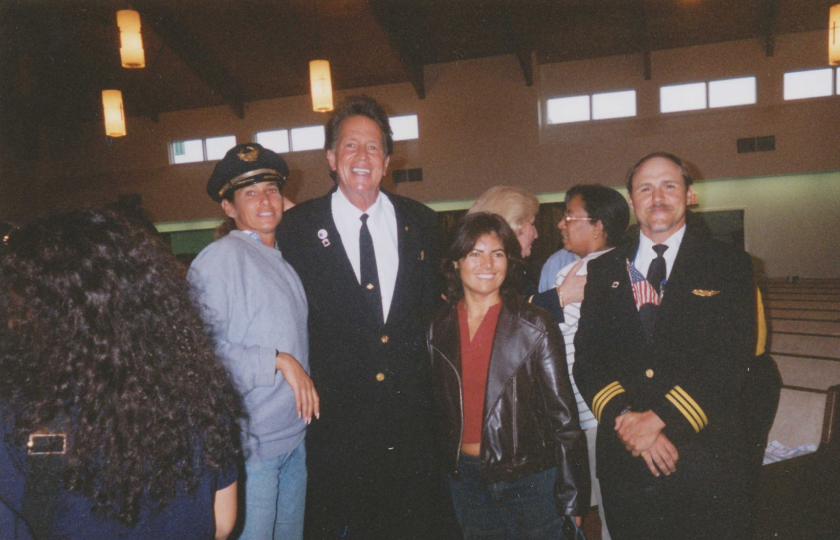 Photograph of civilians posing for a photo alongside a flight crew inside Gander Airport.