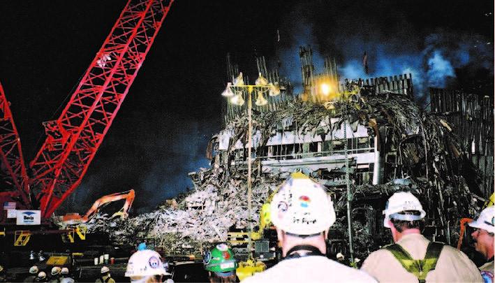 Men in hardhats stand in front of the ruins of the Marriott Hotel at Ground Zero.