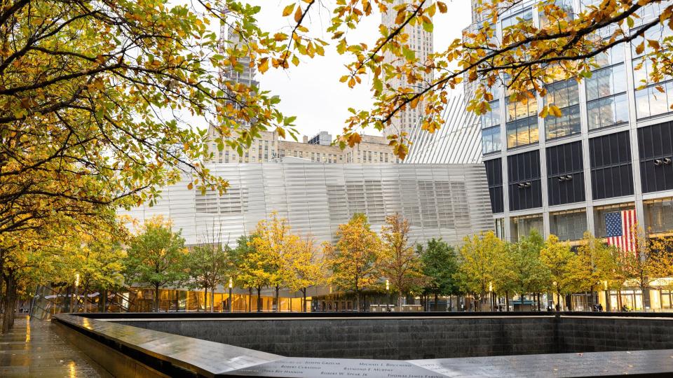 Fall foliage surrounds a Memorial pool, with the Museum exterior in the background and other buildings visible on the right.